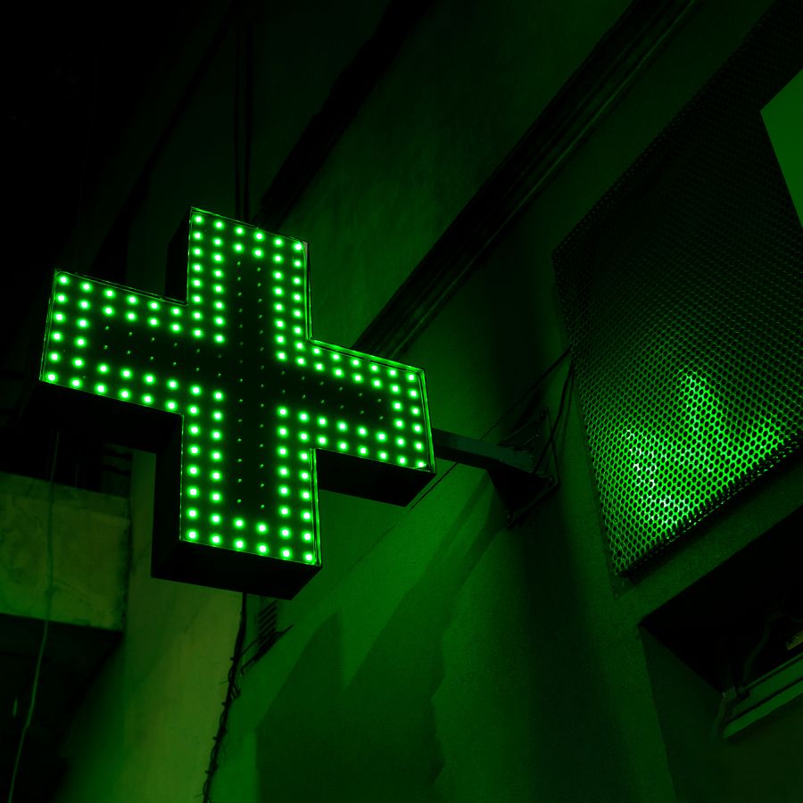 Illuminated green pharmacy cross sign
